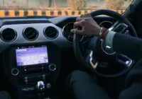Close-up of a car interior with driver's hand on steering wheel in Delhi, India.