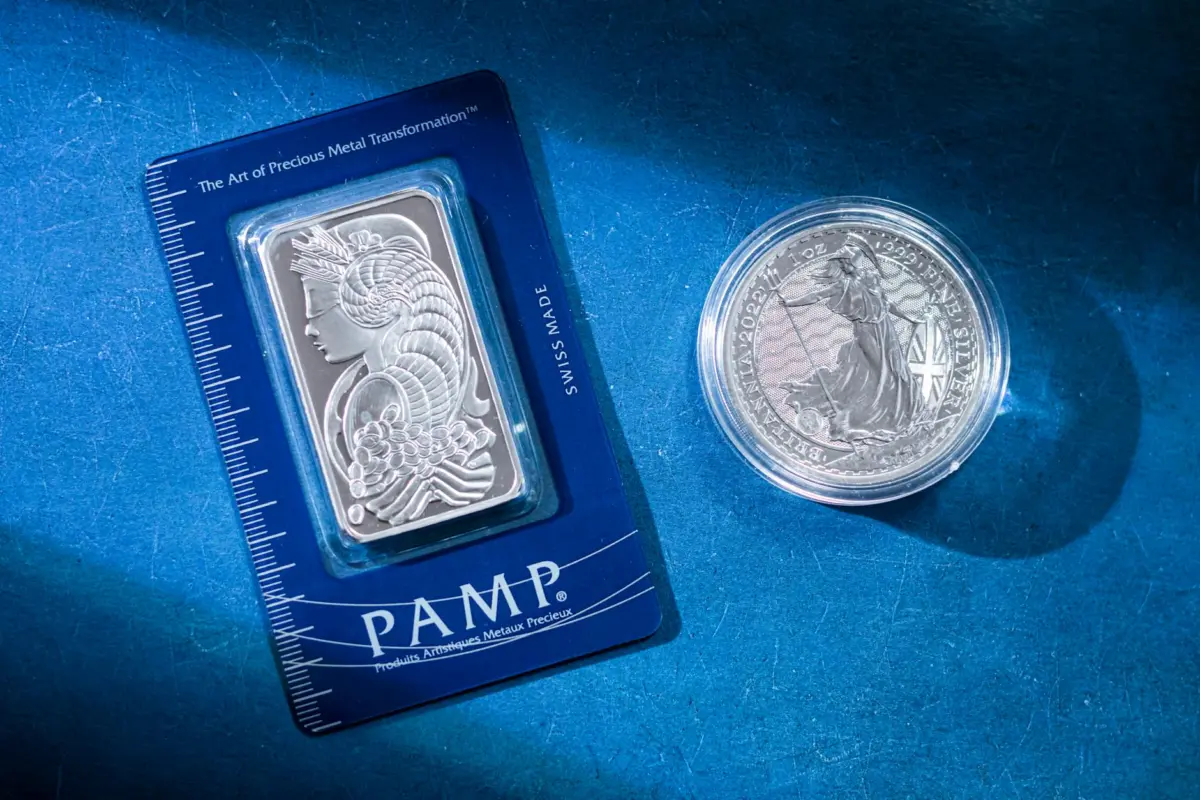 चांदी में निवेश कैसे करें 2026: Physical, Silver ETF, MCX Trading — पूरी गाइड 2 Close-up of a silver coin and a PAMP bar on a blue textured background emphasizing wealth.