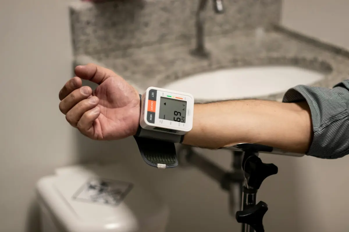 हाई ब्लड प्रेशर कंट्रोल — 12 आयुर्वेदिक उपाय जो असर दिखाते हैं 2 Close-up of an arm using a wrist sphygmomanometer in a healthcare setting.