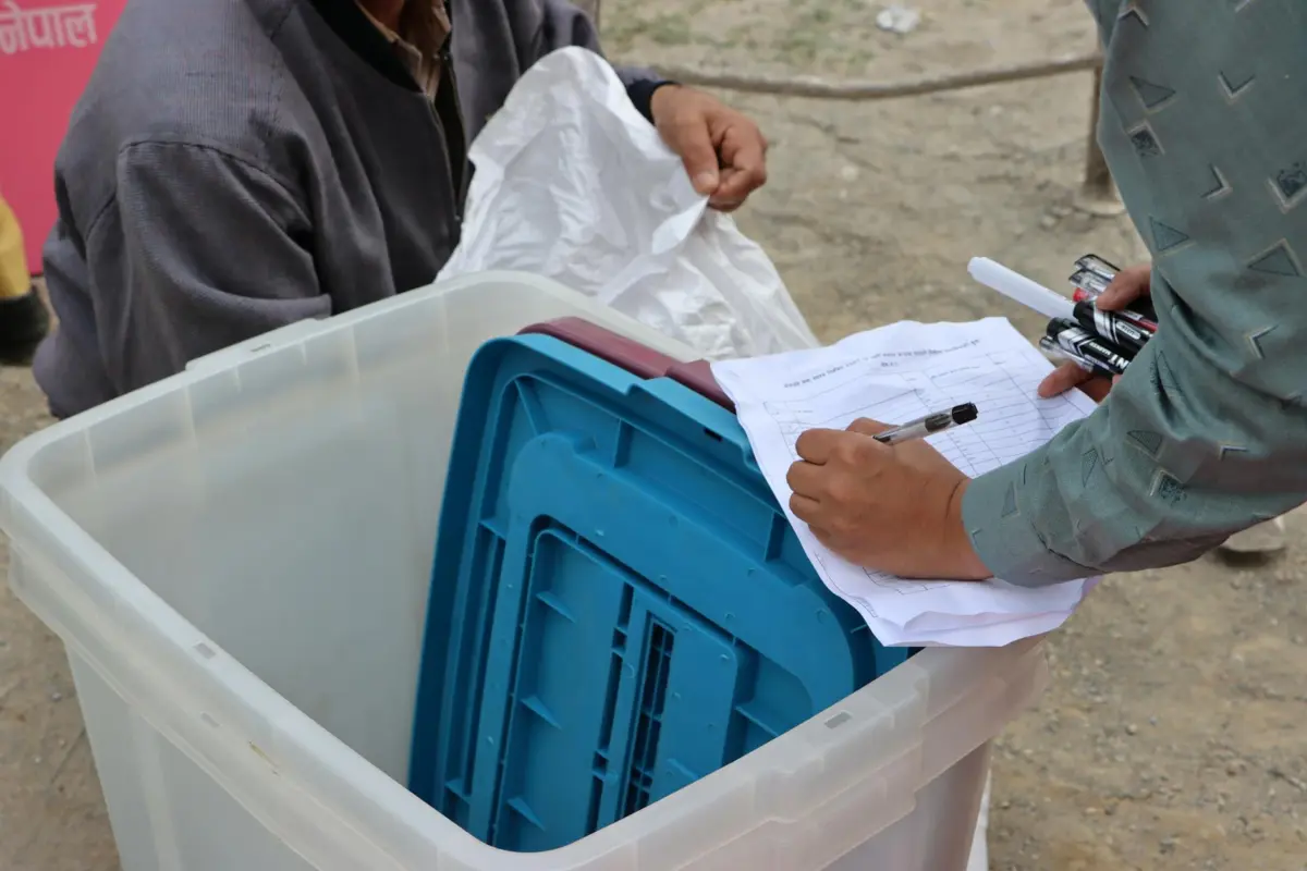 आधार कार्ड में नाम और जन्मतिथि कैसे सुधारें — Step-by-Step 2026 2 Election authorities managing ballot box during Nepal election.