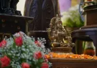 Intricately designed Hindu deity statue with bright floral arrangements indoors.