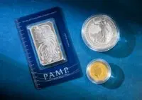 Silver bar and coins on blue surface, highlighting investment and collectible value.
