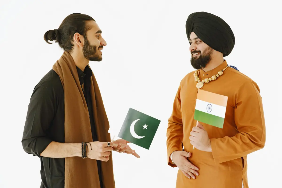 ट्रंप के दूसरे कार्यकाल का भारत पर प्रभाव: H-1B वीज़ा, व्यापार और रणनीतिक संबंध 2 Two men, holding Indian and Pakistani flags, engage in friendly conversation.