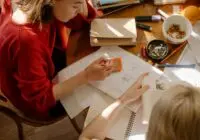 Two students engaged in studying at a table with textbooks, notes, and stationery.