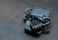 Close-up of a smartphone wrapped in a chain with a padlock, symbolizing strong security.