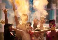 A group of boys celebrating Holi in Bihar, India with colorful powder clouds.