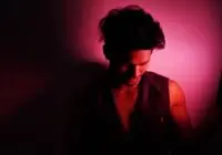 A moody portrait of a man bathed in vibrant red light, creating a dramatic effect.