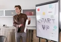 A young entrepreneur gives a presentation on startup strategies indoors with a flip chart.