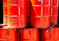 Bright red industrial oil barrels stacked outdoors in daylight, showcasing vivid color and industrial theme.