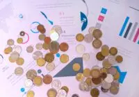 Image of various coins on financial documents with graphs and charts.