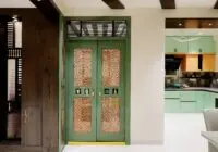 Interior view featuring a stylish Indian home entrance with intricate door designs leading to a modern kitchen.