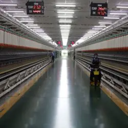 Long hallway in Indian textile factory with spinning machinery and workers.