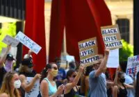 Protesters gather with signs supporting Black Lives Matter and denouncing Donald Trump in a peaceful rally.