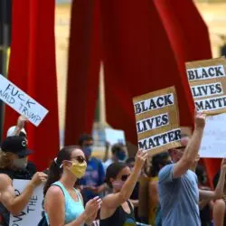 Protesters gather with signs supporting Black Lives Matter and denouncing Donald Trump in a peaceful rally.
