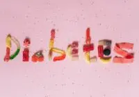Candies shaped to spell diabetes on a pink background, highlighting sugar intake