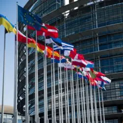 BRICS विस्तार 2026 — भारत के लिए रणनीतिक मायने और वैश्विक प्रभाव 25 Flags of European Union countries outside a modern building facade.