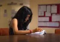 Focused young woman reading a textbook at a university library desk in New Delhi.