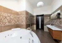 Interior of contemporary bathroom with round ceramic bathtub and sink and wooden cabinet in daytime