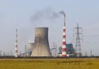 Smokestacks and a cooling tower emit smoke at a power plant in Vijayawada, India.