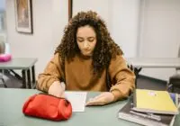 Young woman studying for an exam in a college classroom with books and notes.