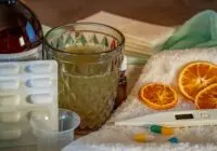 A collection of home remedies and medications for treating cold and flu symptoms, including a thermometer, pills, and herbal tea.